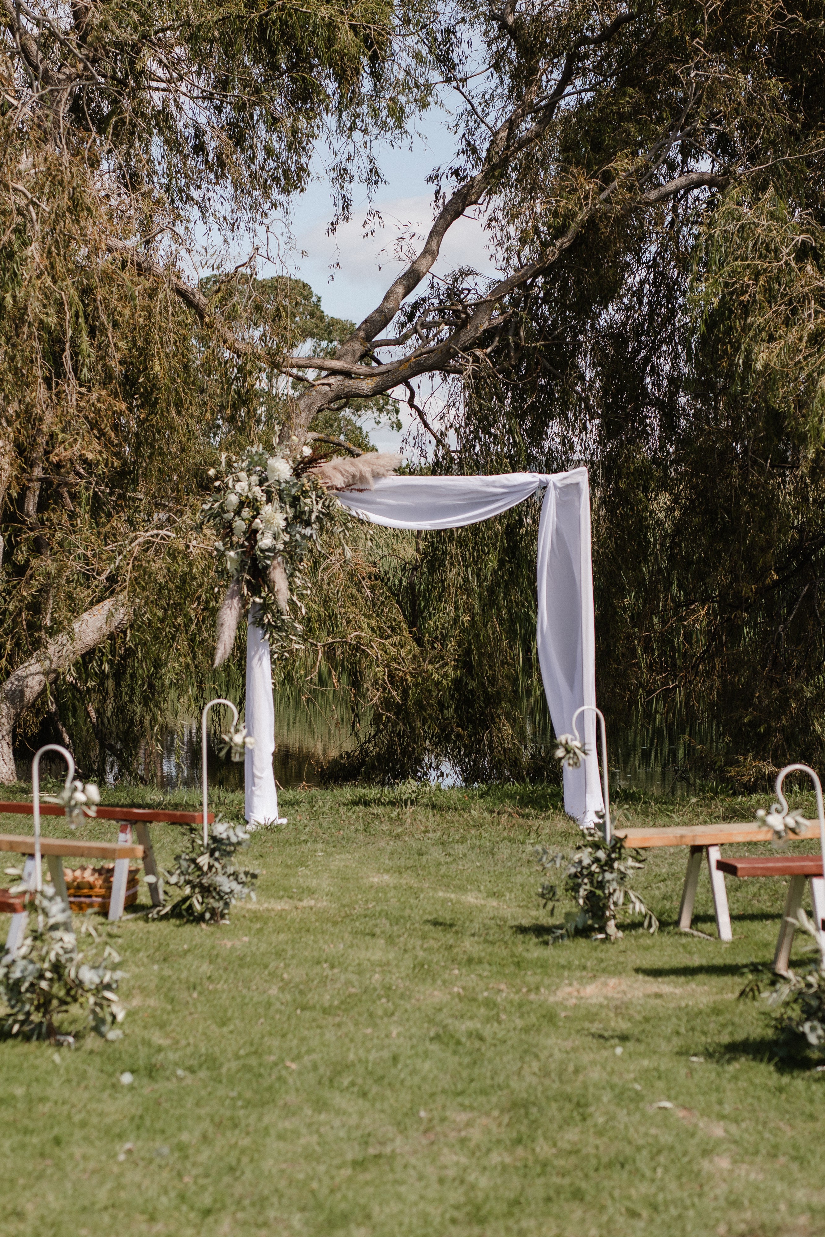 A wedding arch set in front of a large willow tree